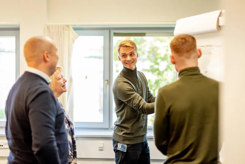 Mand viser noget på tavle til kolleger