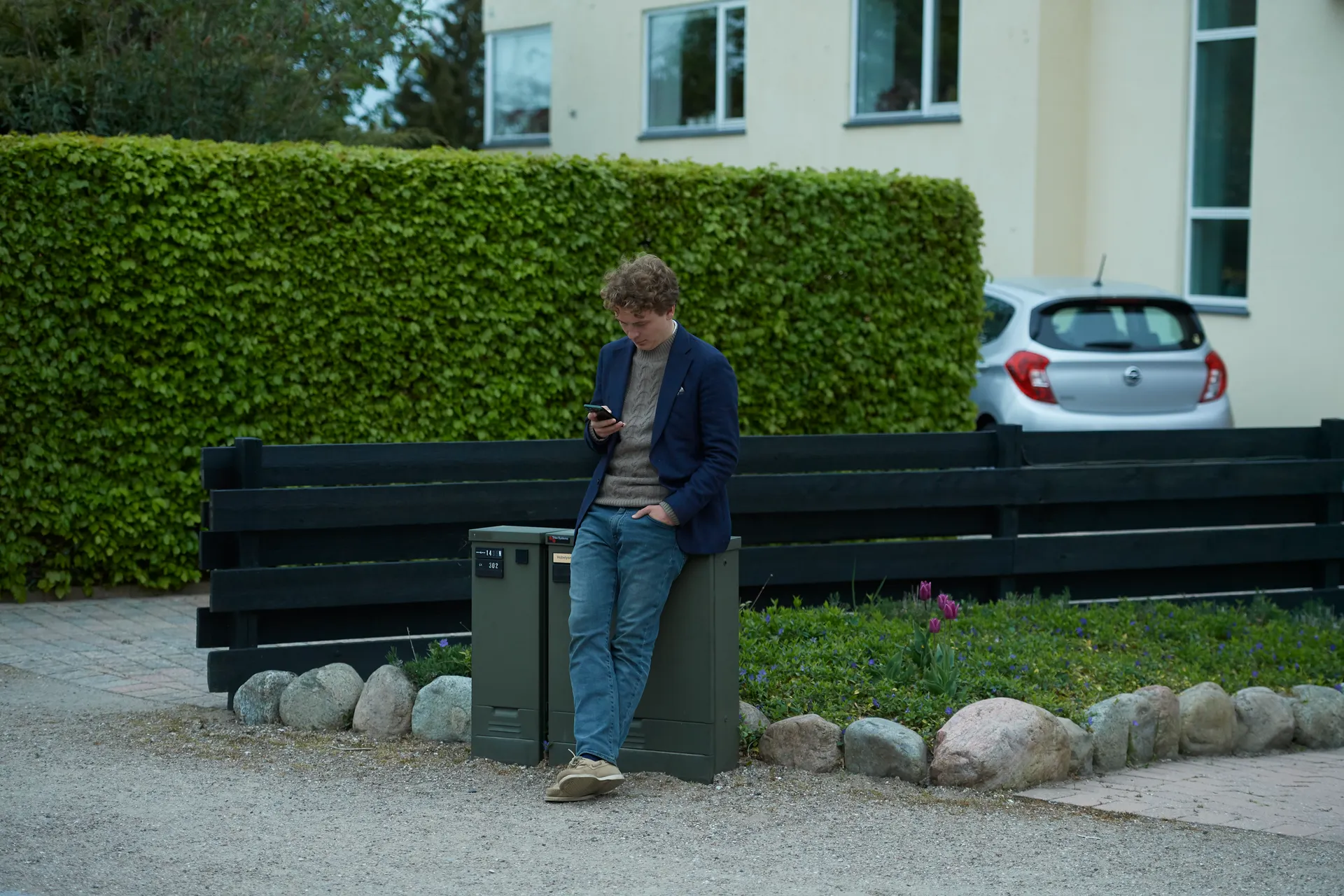 En mand der læner sig op af et kabelskab og kigger på sin telefon