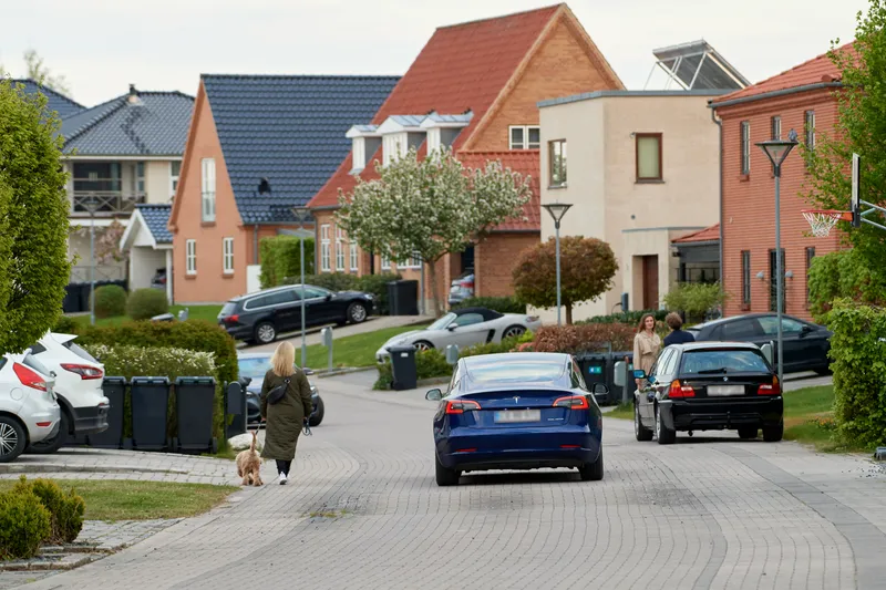 En elbil kører ned ad en villavej