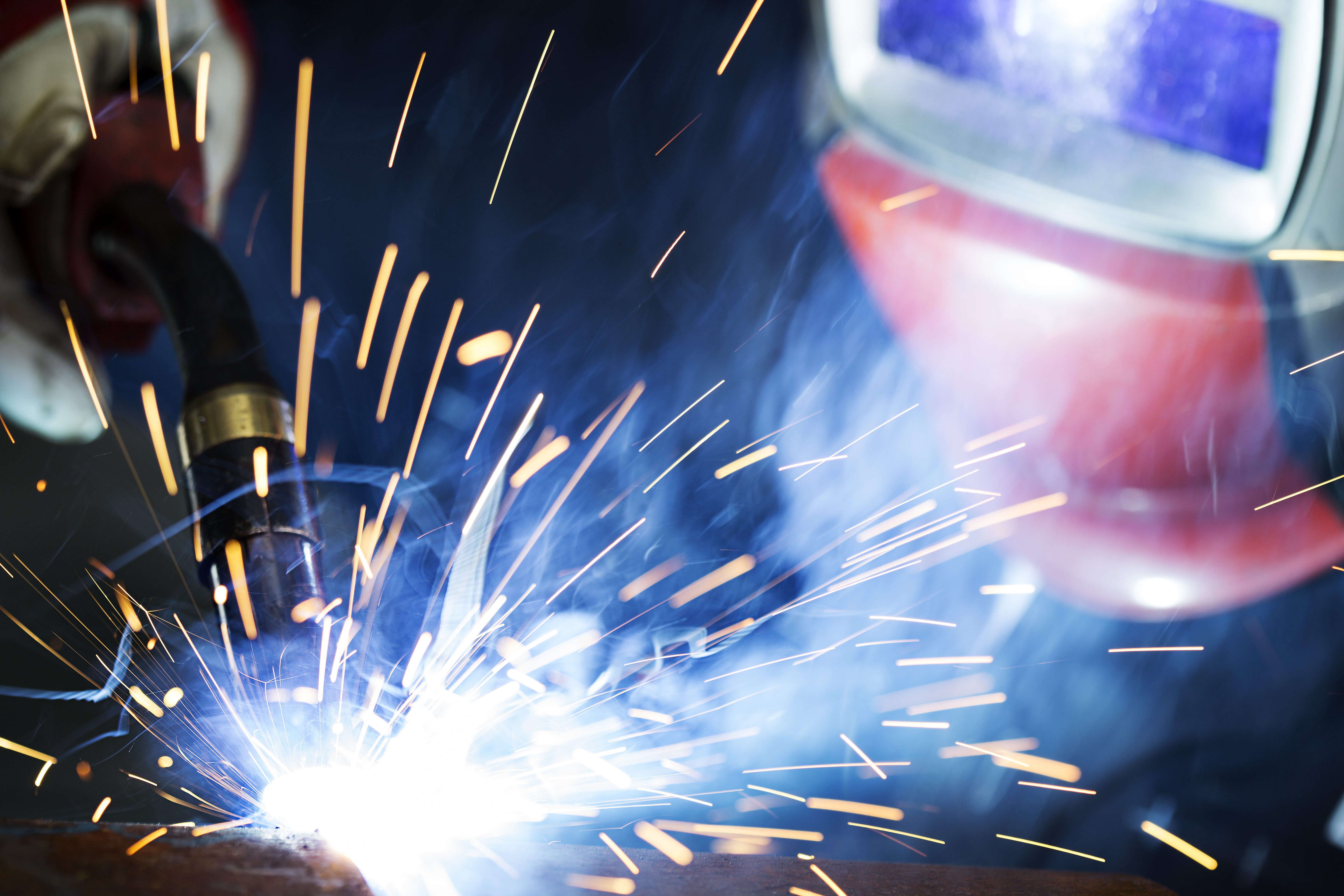 A welding specialist performs a controlled welding trial on a steel component to validate a new welding procedure under realistic conditions.