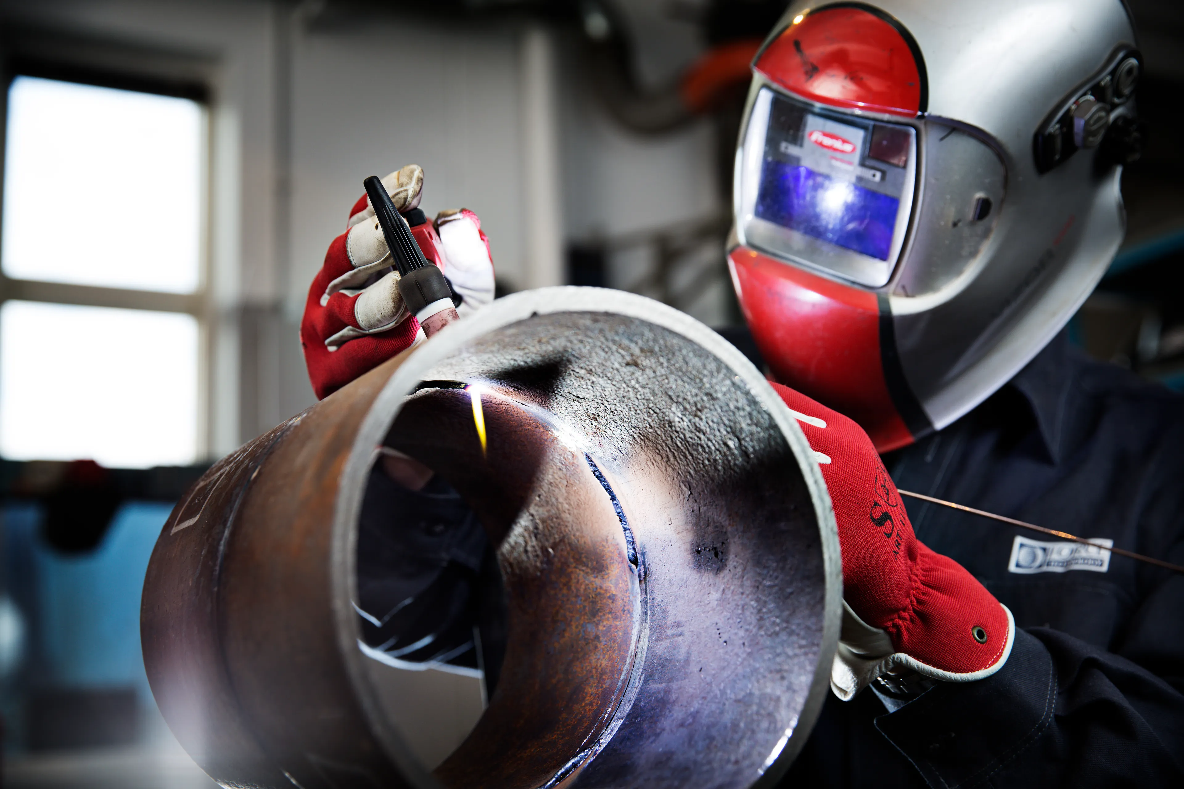 Close-up of a welder performing a weld on a metal component.