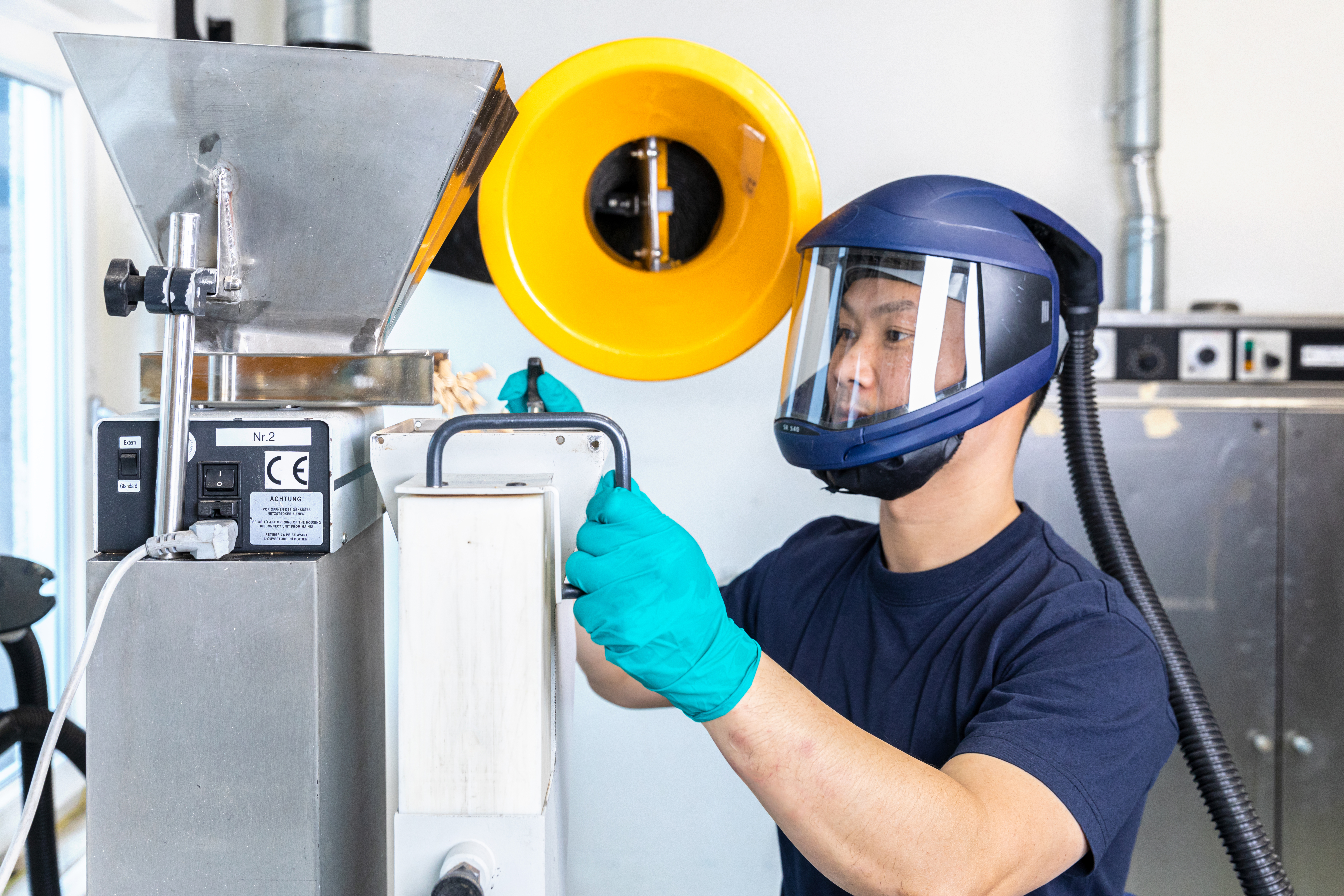 Technician examining fuel or residue samples in a laboratory setting.