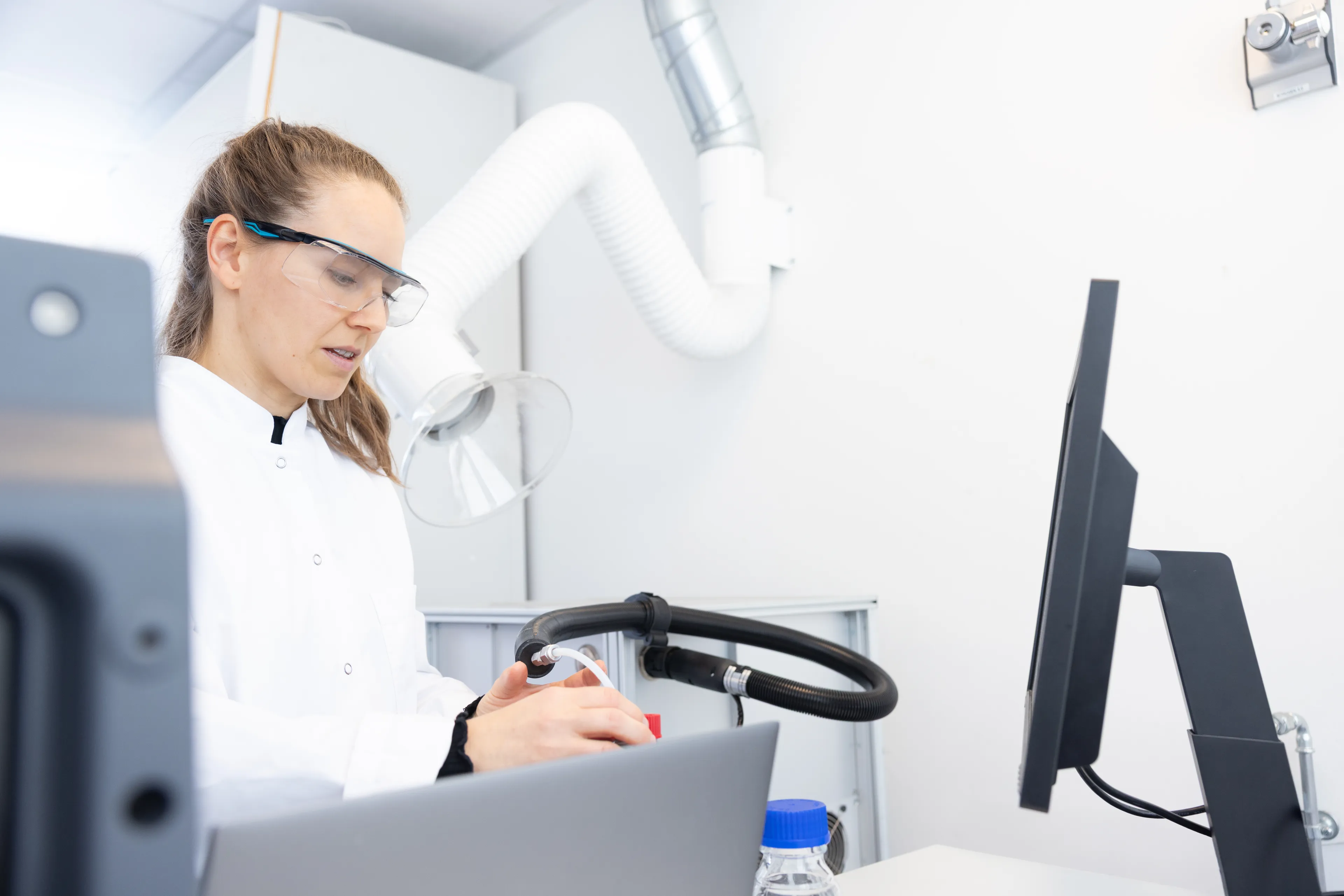 Technician analysing building material samples in a structural survey laboratory using microscope and laboratory equipment. 