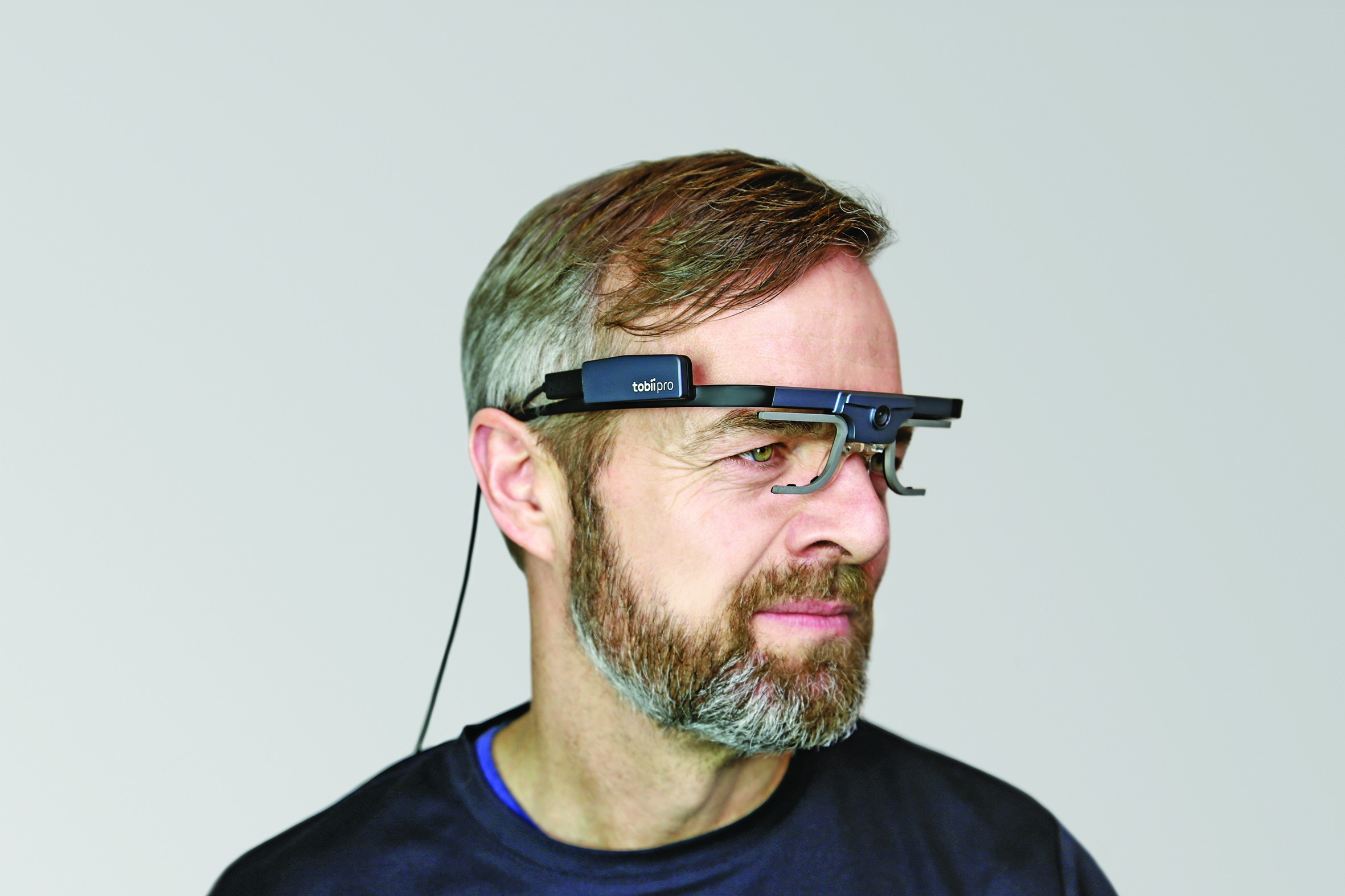 Mand iført eye-tracking briller med frontmonteret kamera og sensorenhed.