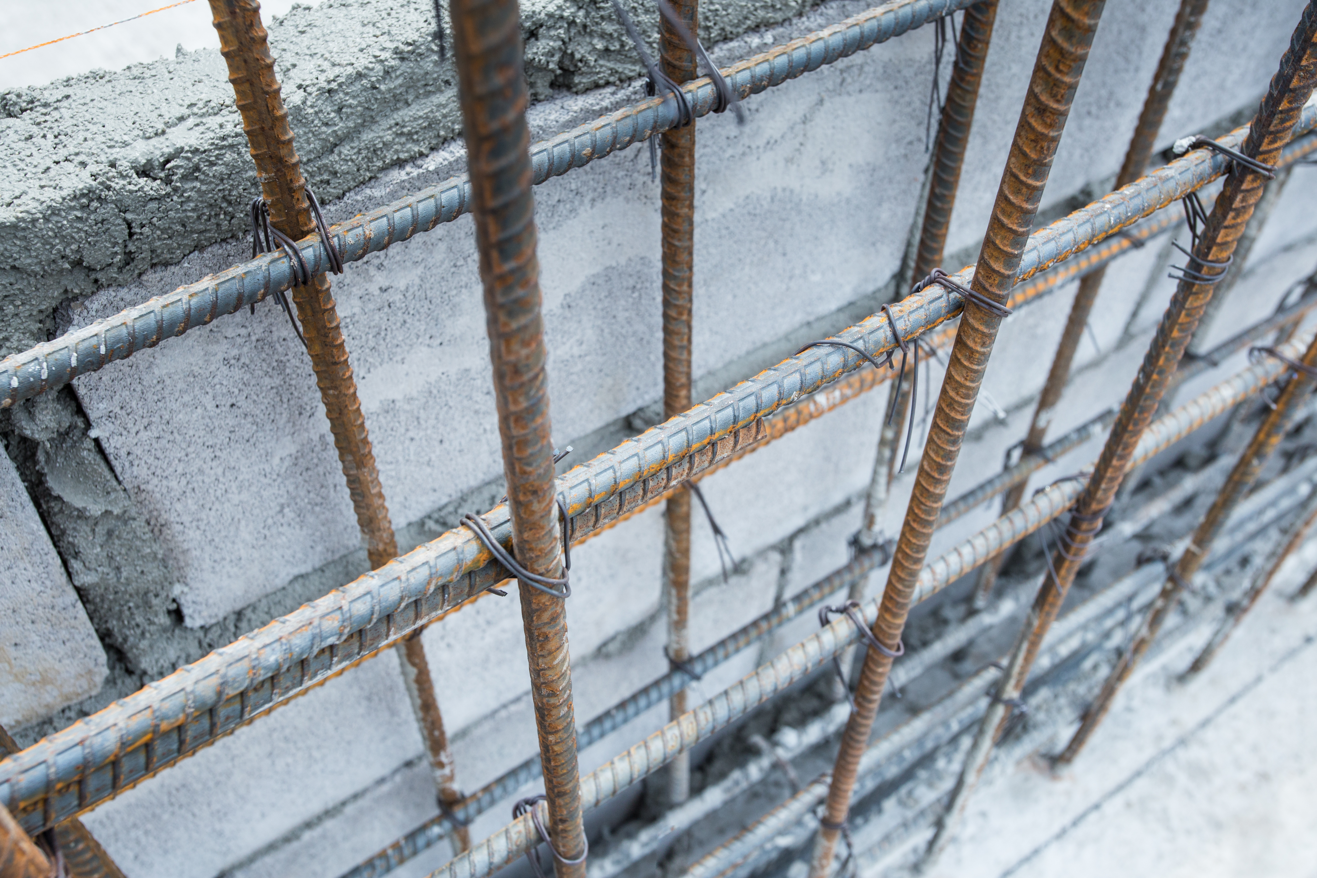 Close-up of steel reinforcement bars in a grid inside a concrete structure, showing early surface corrosion relevant to cathodic protection of reinforced concrete.