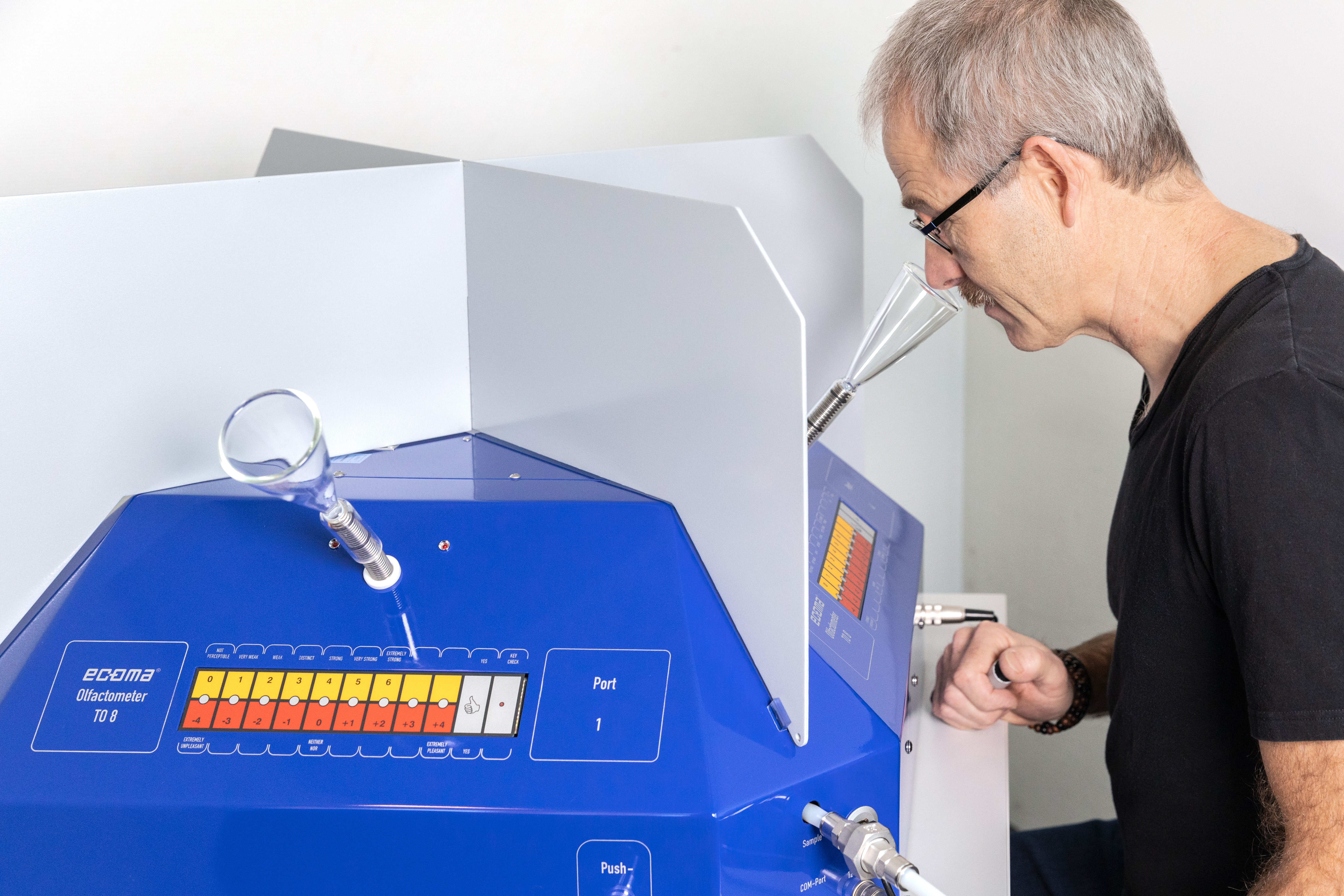 Person leaning towards a laboratory device while assessing odour samples as part of an odour panel test.