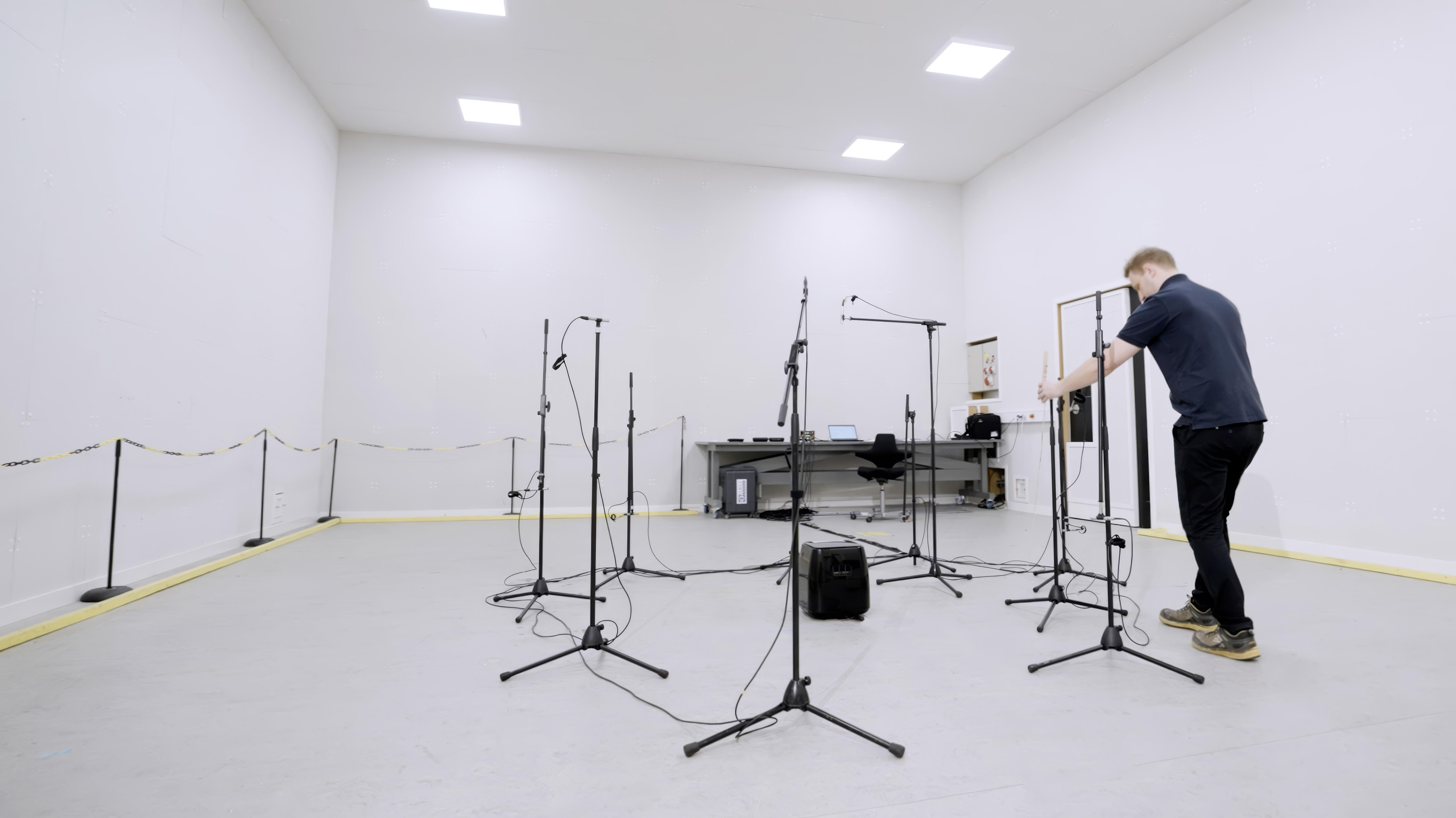 Technician preparing microphones and measurement equipment for accredited noise and vibration testing in an acoustic test room.