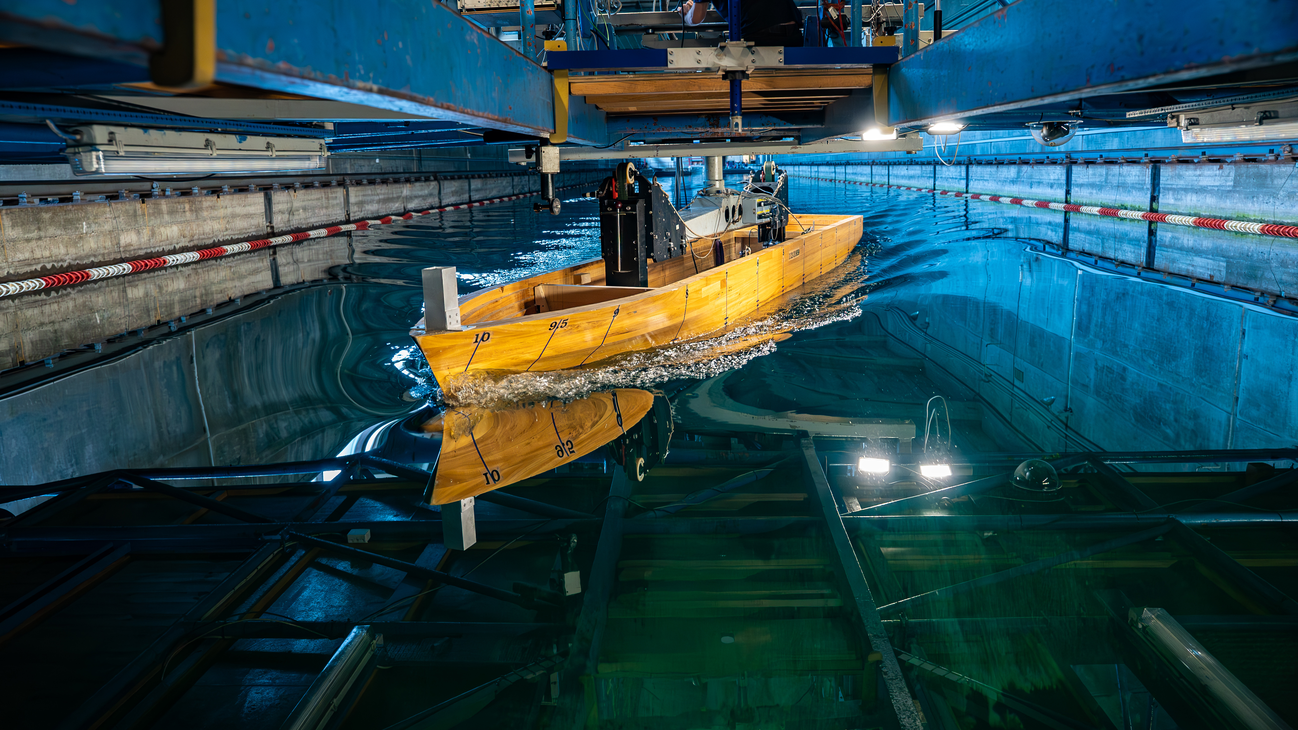 Wide towing tank with a free-sailing ship model during seakeeping evaluation testing under controlled wave conditions.
