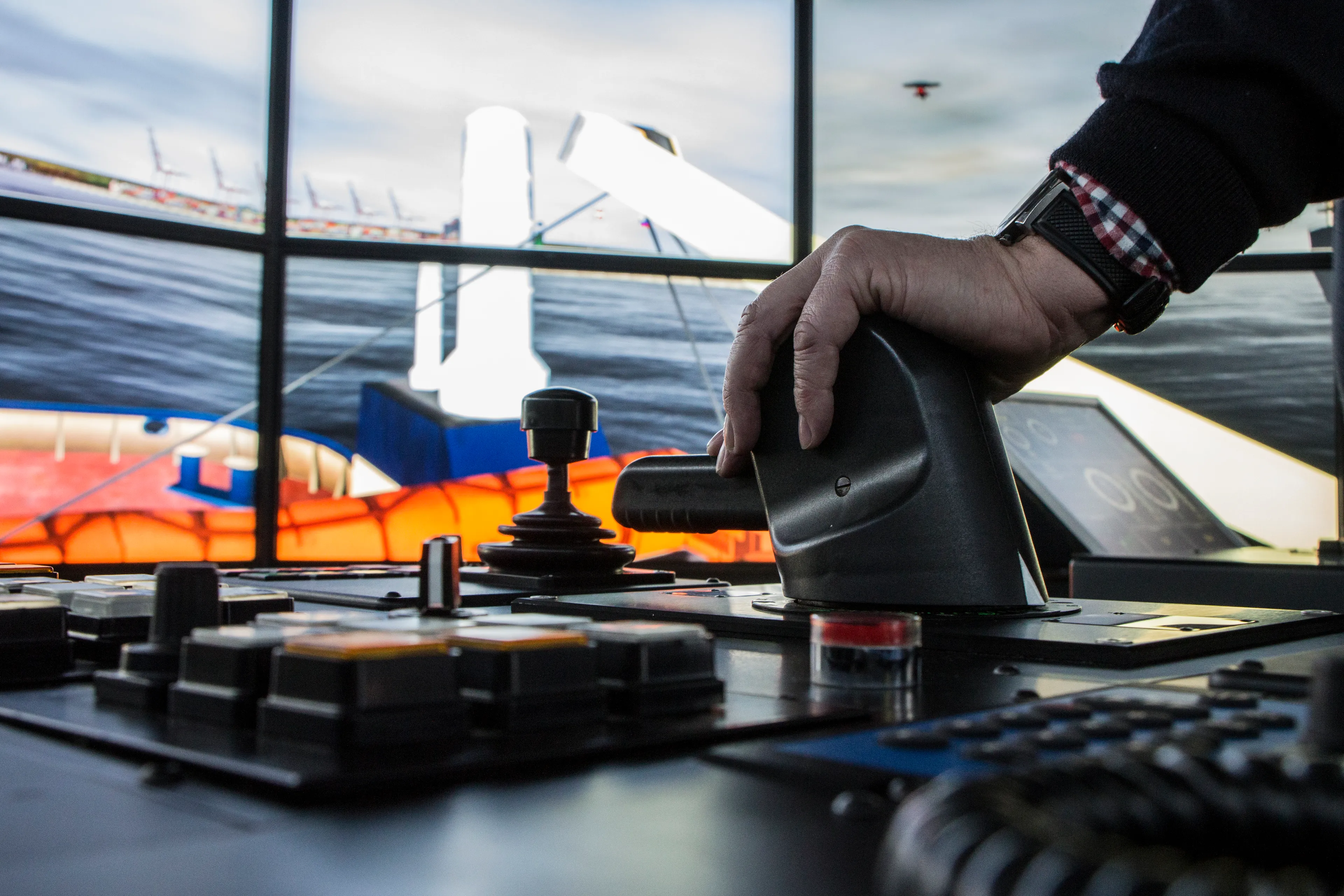 Nærbillede af en person, der betjener et skibssimulator-kontrolpanel under navigationsrisikoanalyse af en planlagt maritim operation. 